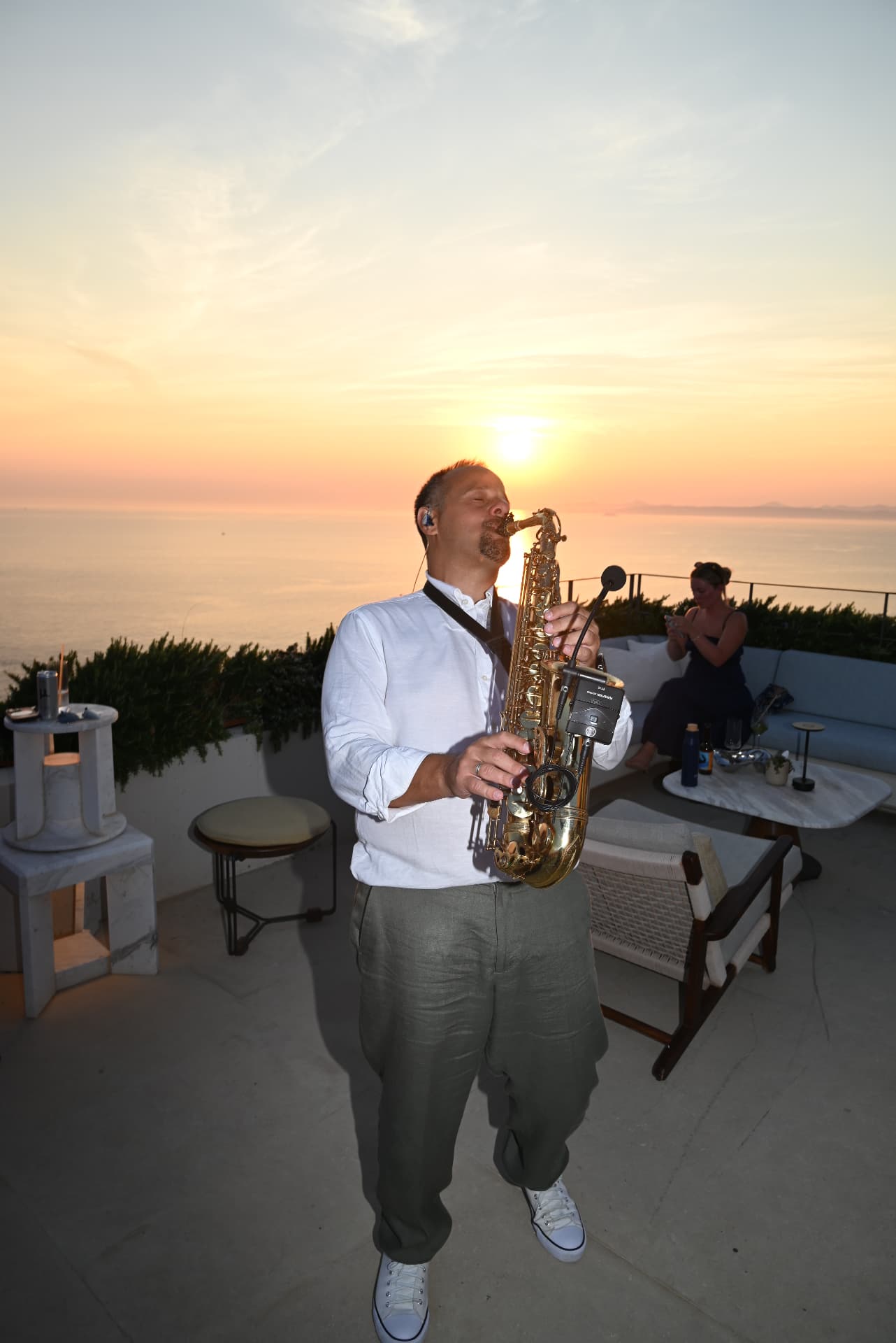 Saxophonist playing at sunset on a rooftop terrace over the sea